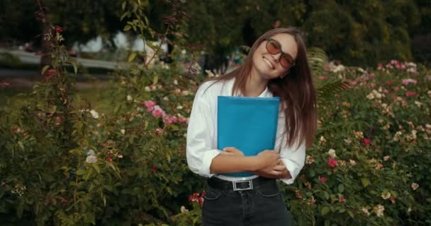 화창한 날 Wih A 폴더에 휴가에 공원에서 선글라스에 아름 다운 세련 된 세련 된 젊은 여자 — 비디오