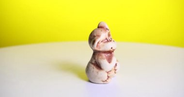 Oyuncak kahverengi maymun beyaz bir masada döner. Sarı arka plan. ProRes 4k