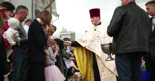 KAMENKA-BUZKA, UKRAINE - APRIL 2019: Masyarakat, anak-anak, imam memercikkan air suci, memberkati keranjang Paskah, kulich, paska, pascha, telur di Biara Nasional Katolik Ukraina Gereja Keluarga Kudus — Stok Video