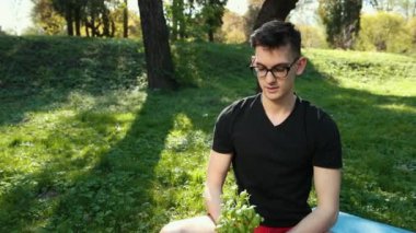 Kap içinde yetişen Basil 'in genç tohumları, Sağlıklı ve yoğun yeşil yapraklar. Gözlüklü genç bir adam iki leğen fesleğeni iki eliyle tutuyor ve ona hayret ediyor. Sağlıklı bir yaşam tarzı kavramı. Dualar