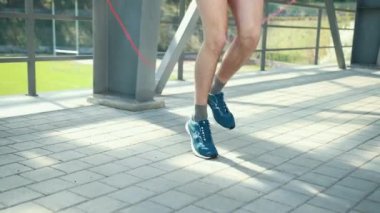 Konforlu Spor Giysileri Giyen Genç Sporcu Metal Rafları 'nın yanındaki bir spor sahasında İp Atlıyor. Stadyumun arka planında ip atlama egzersizi yapan çocuk. Fitness Erkek Egzersiz Yapıyor