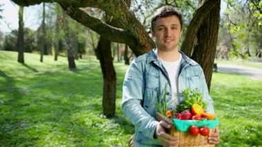 Mutlu genç bir çiftçi taze sebze bir sepeti tutan portresi. Arka plan doğa biyolojik, biyolojik ürünler, biyo ekoloji, kendi elleriyle, vejetaryen, salata sağlıklı yetiştirilen kavramı üzerinde