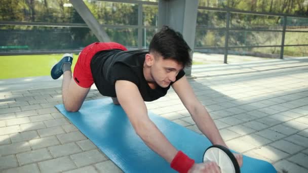 El hombre en el gimnasio está involucrado en una rueda para la prensa . — Vídeos de Stock