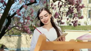 şık Sakura arka planda sokakta tuval üzerinde fırça boyama resmi ile sanatçı WOMANS el.
