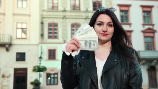 Bella ragazza in occhiali neri sulla fronte solleva un mucchio di dollari e li ha creando un vento con un viso soddisfatto . — Video Stock