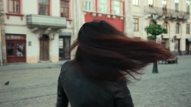 Vacker ung brunett flicka snurrar framför kameran leende och hennes hår svettningar och snurrar i vinden. ProRes, slow motion — Stockvideo