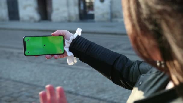 Mädchen spricht auf einem Smartphone den Greenscreen des Telefons an. winkt den Menschen zu, die sie auf dem Bildschirm sehen. Spaß haben, Technologien. Nahsicht, Zeitlupe. prores — Stockvideo