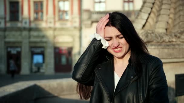 Zmęczona kobieta ból głowy. Portret zdenerwowany dziewczyna dotykając głowę ręką w ulicy. Zbliżenie z podkreślił twarz dziewczyny, 4K — Wideo stockowe