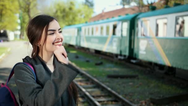 Een mooi en gelukkig meisje staande in de voorkant van de trein wagon houdt een kaartje in haar handen en zegt vaarwel tegen haar geliefde persoon en familieleden voor vertrek. — Stockvideo