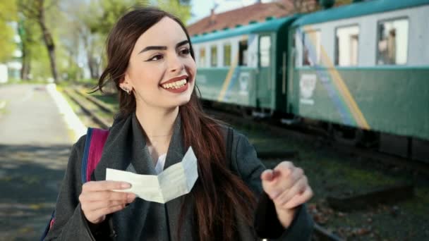 Привлекательная молодая женщина путешествует на поезде, смотрит на купленный билет для поездки и ищет номер своего вагона . — стоковое видео
