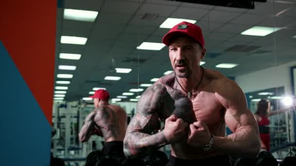 Um belo atlético masculino fisiculturista mostra músculos — Vídeo de Stock