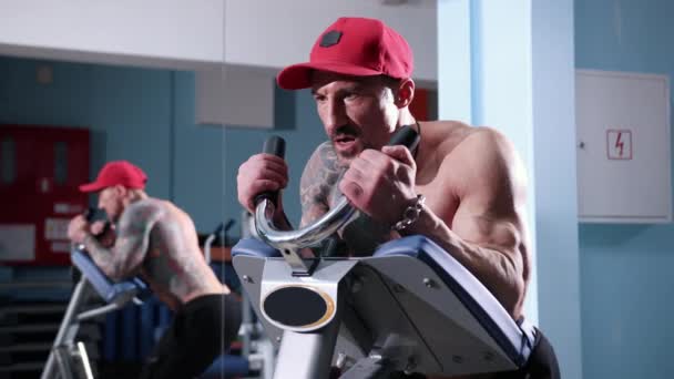 Muscular man on sports equipment pumping press and muscles on his feet in gym. — Stock Footage Muscular man on sports equipment pumping press and muscles on his feet in gym. Royalty Free Stock Video
