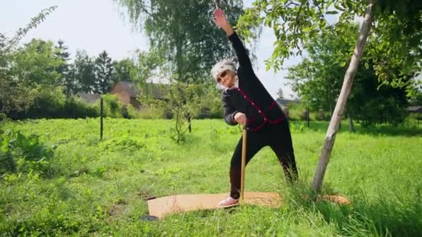 Olld mulher segura a mão na vara e realizar exercícios físicos encostados — Vídeo de Stock