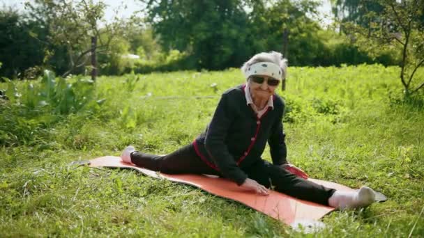 Pensioner grandmother sits on longitudinal splits, looks into camera — Stock Footage Pensioner grandmother sits on longitudinal splits, looks into camera Stock Footage