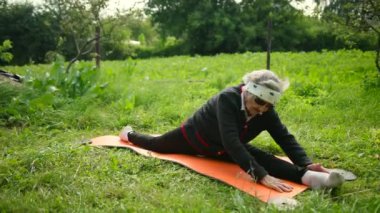 Uzunlamasına bölünmeler yoga minderi üzerinde oturan güneş gözlüğü takan yaşlı kadın