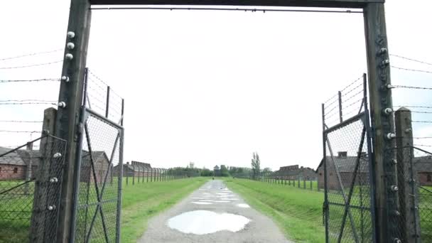 Entrance gate and the electric fence of the concentration camp with barracks — Stock Video