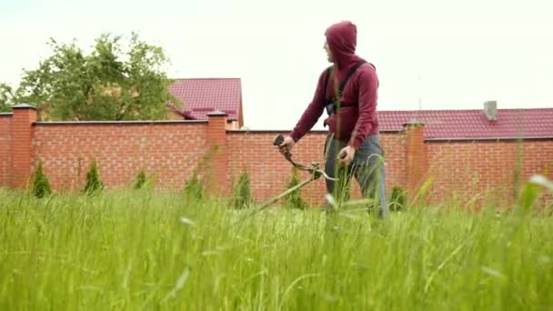 Persoon maait het gazon met een benzine grasmaaier, de camera schiet in het gras — Stockvideo