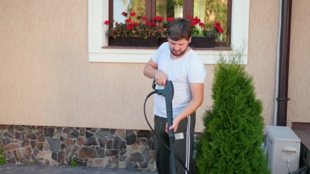 Un homme en t-shirt blanc lave les pavés avec un jet d'eau haute pression — Video