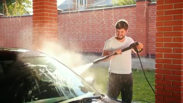 Samec myje auto mytím auta pomocí vysokotlaké vodní proudové vody. na dvoře — Stock video