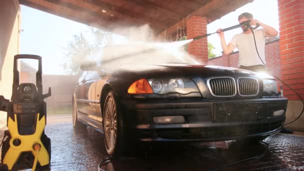 Munkás mossa autó. nagy nyomású vízsugarat használunk, fröccsenés az oldalra — Stock videók