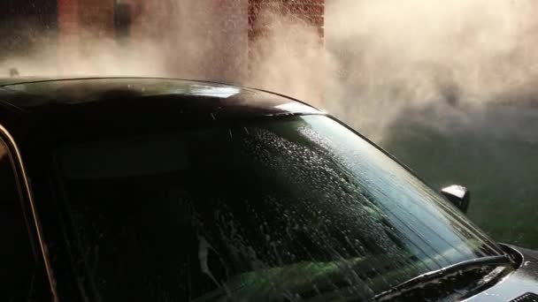 Persona lava el coche, lavar con chorro de agua de alta presión. salpicaduras diseminadas a los lados — Vídeo de stock