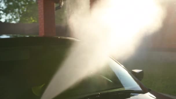 El hombre lava el coche a fondo. lavar con chorro de agua de alta presión. sol brilla — Vídeo de stock