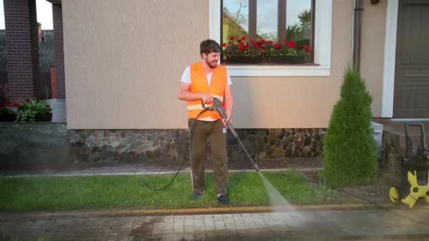 Очиститель в оранжевом жилете, мыть тротуары промывают струями воды высокого давления . — стоковое видео