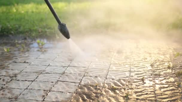 Man reinigt in de buurt van huis, wast pavers, gebruikt wassen met hoge druk waterstralen — Stockvideo