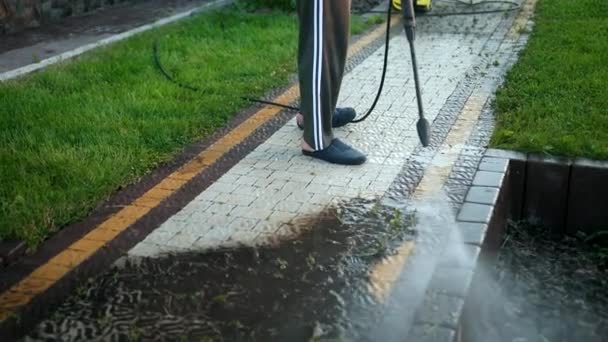 Male, cleaner, washes cobblestones with a jet of high pressure water, close-up — Stock Video