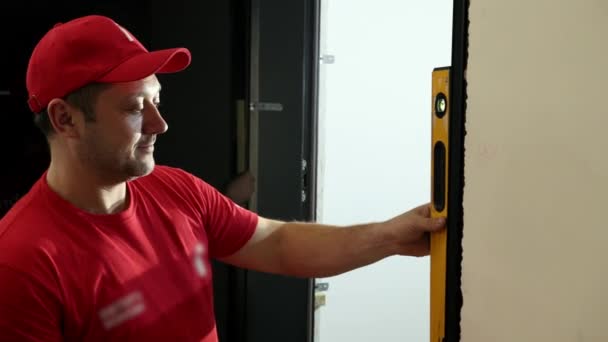 Man Builder uses bubble level rulers of Clinometer to measure evenness of a wall — Stock Video