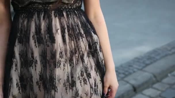 Дівчина в чорній елегантній сукні з мереживом, кружляючи на вулиці, крупним планом — стокове відео