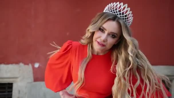 Mädchen, blond, in einem roten Kleid, eine Krone auf dem Kopf, posiert für die Kamera — Stockvideo