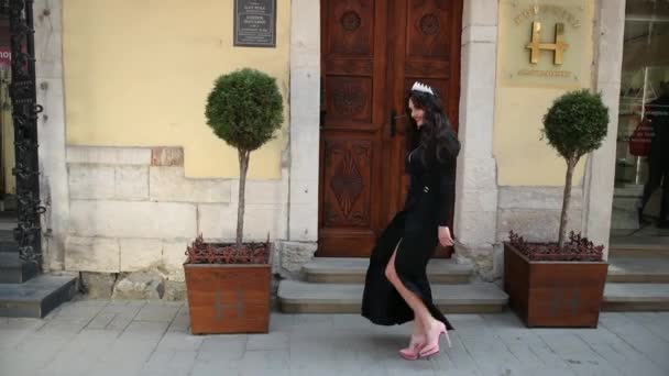 Flicka, brunett, i en svart klänning med en djup urringning, med smink, med en krona — Stockvideo