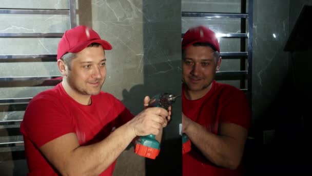 A man, a Builder, in a red cap and t-shirt, uses a cordless screwdriver — Stock Video