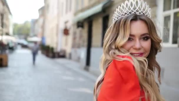 Fille, blonde, dans une robe rouge, une couronne sur la tête, posant pour la caméra — Video