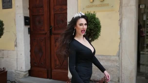 Брюнетка, в черном платье с глубоким вырезом, с макияжем, с короной — стоковое видео