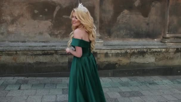 Flicka, blondin, i grön klänning med bara axlar, med krona, poserar för kamera — Stockvideo
