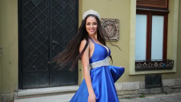 Miss, bruna, in un abito blu con una scollatura profonda, con una corona, in posa — Video Stock