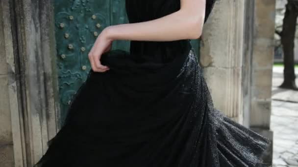 Стройная девушка, в черном эффектном платье, позирует и крутится перед камерой — стоковое видео