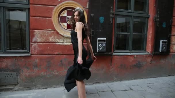 Chica, morena, vestido negro, con maquillaje brillante, corona, posando en la calle — Vídeos de Stock