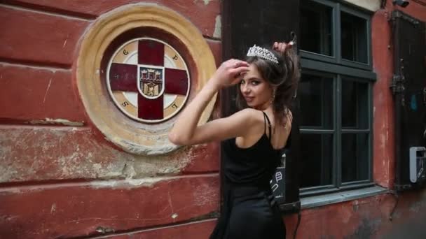 Señorita, morena, vestido negro, con maquillaje brillante, corona, posando en la calle — Vídeos de Stock