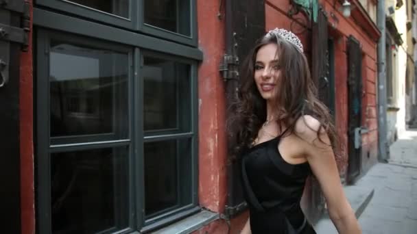 Ragazza, bruna, in abito nero, con trucco luminoso, corona, camminare per strada — Video Stock