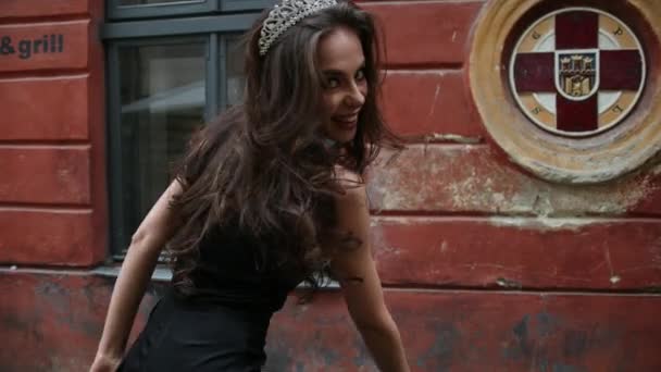 Girl, brunette, in black dress, with bright makeup, crown, walking on the street — Stock Video