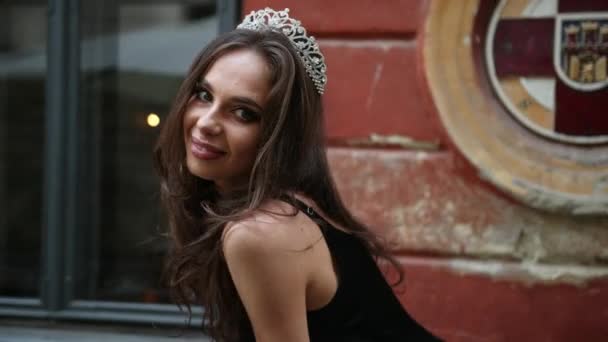 Slečna, bruneta, černé šaty s jasným make-upem, korunou, pózovaná na ulici — Stock video