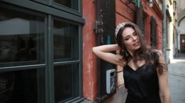 kız, esmer, siyah elbise, parlak makyaj, taç, sokakta poz ile