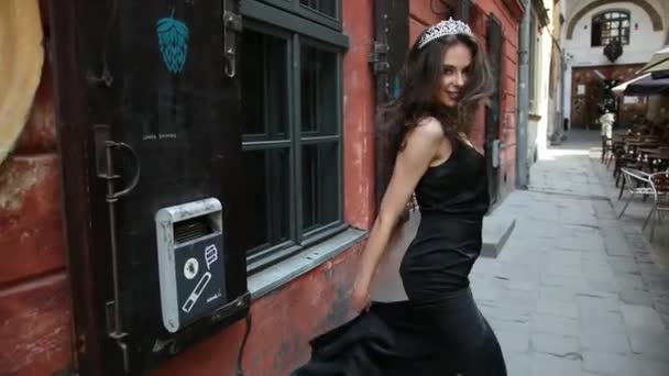 Chica, morena, en vestido negro, con maquillaje brillante, corona, caminando por la calle — Vídeos de Stock