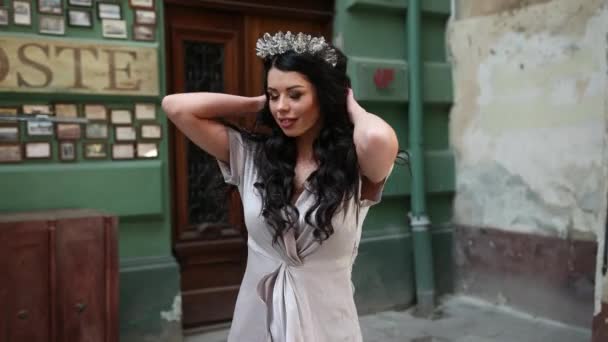 Brunette girl, in gray dress, slender legs, bright makeup, crown on head, posing — Stock Video