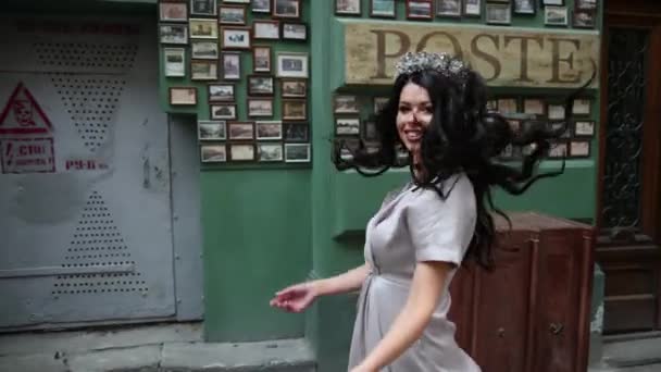 Brünettes Mädchen, im grauen Kleid, schlanke Beine, helles Make-up, Krone auf dem Kopf, posierend — Stockvideo