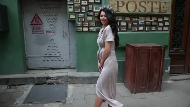 Chica morena, en vestido gris, piernas delgadas, maquillaje brillante, corona en la cabeza, posando — Vídeos de Stock