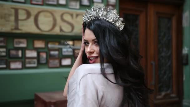 Chica morena, en vestido gris, piernas delgadas, maquillaje brillante, corona en la cabeza, posando — Vídeos de Stock